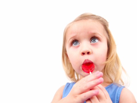 a toddler girl eating candy isolated on white.