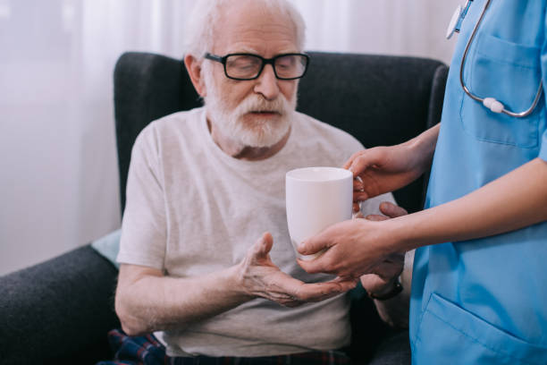 istock Nurse giving cup with drink to senior patient 932326730