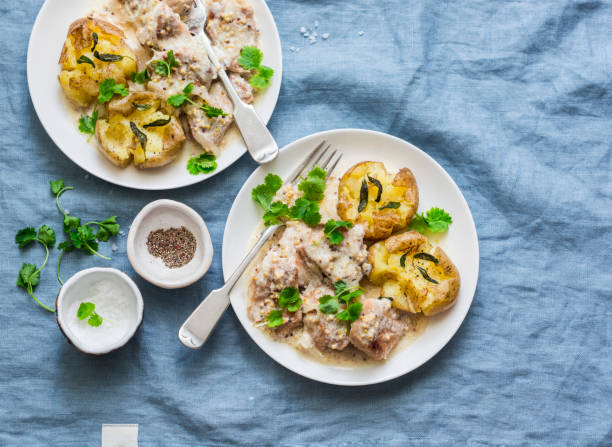 zertrümmert salbeibutter gebratene kartoffeln und fleisch senf-sahne-sauce - leckeres mittagessen auf blauem hintergrund, ansicht von oben - smashed potatoes stock-fotos und bilder