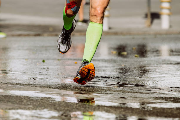 istock feet runner in compression socks running puddles of water 932334268