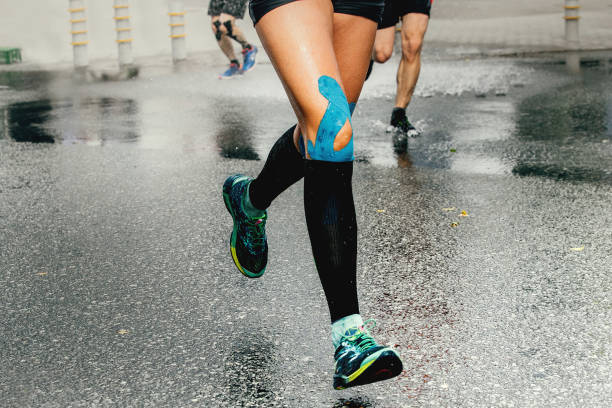 ноги бегун женщина с кинезио ленты и сжатия носки - kinesio стоковые фото и изображения