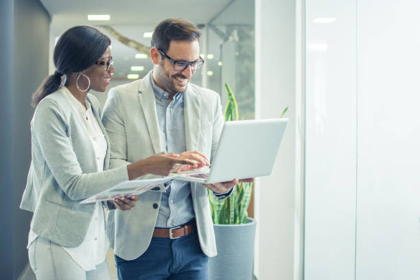 istock Two smiling business people with laptop discussing about new project in office 932334676