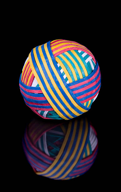 élastique ballon sur une surface noire - rubber band rubber intertwined flexibility photos et images de collection