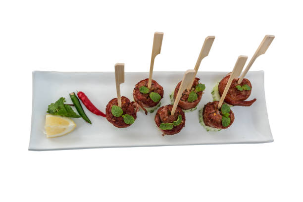 Sour pork wrapped with bacon cooked served with cucumber chili and lime on white dish isolated