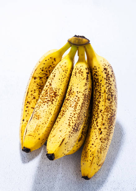 branch of overripe bananas with black dots on the table. natural sweetener. concept of a healthy lifestyle branch of overripe bananas with black dots on the table. natural sweetener. concept of a healthy lifestyle bruised fruit stock pictures, royalty-free photos & images