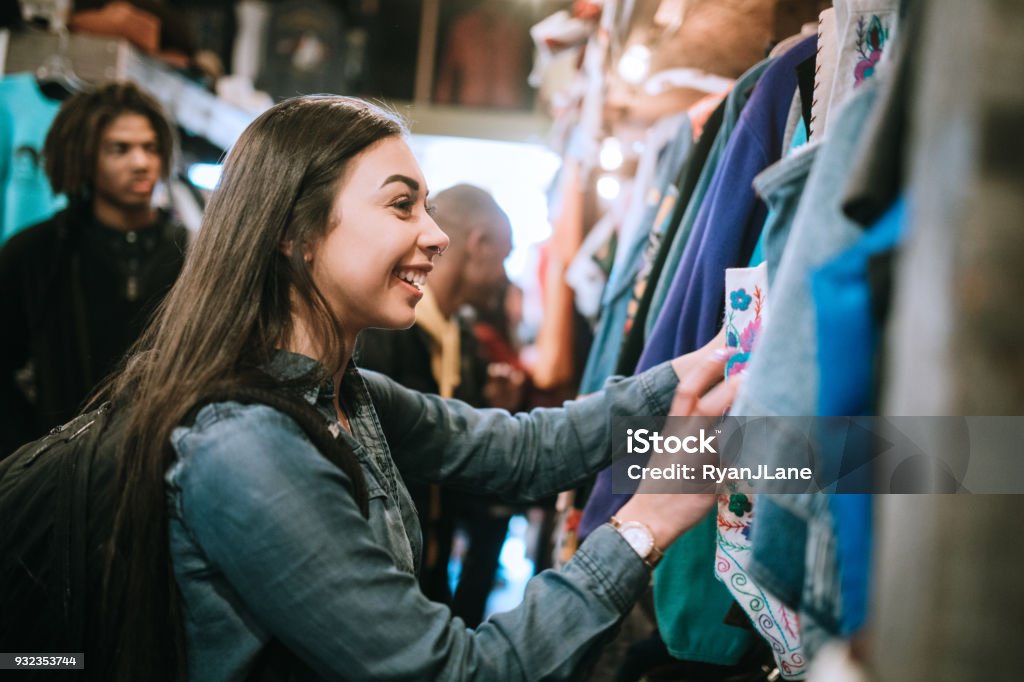 Young Adults Shop For Clothes at Thrift Store A smiling group of young adults have fun shopping for retro and vintage clothing styles at a second hand thrift store.  Mixed ethnic group.  Horizontal image with copy space. Shopping Stock Photo