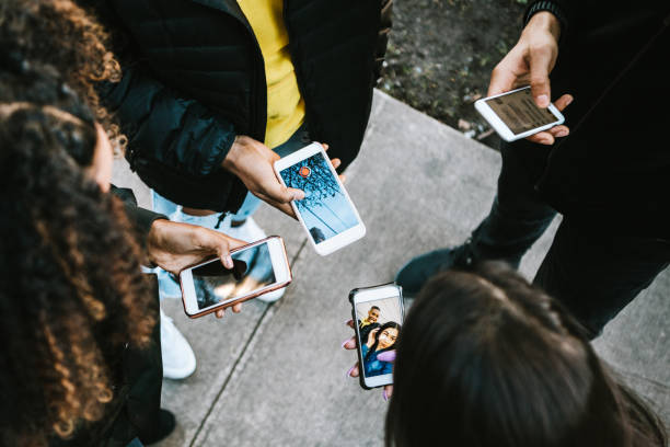 Group of Young Adults Looking at Phone A young adults all viewing something on their smart phones.   Mixed ethnic group.  Horizontal image, as viewed from above.  Faces not visible. generation z stock pictures, royalty-free photos & images