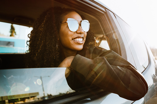 A smiling group of Generation Z young adults enjoy a road trip on a sunny day.  Mixed ethnic group.  Horizontal image with copy space.