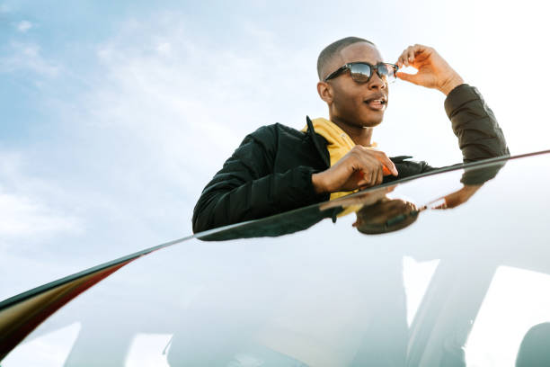 A smiling group of Generation Z young adults enjoy a road trip on a sunny day.  Mixed ethnic group.  Horizontal image with copy space.