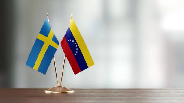 istock Swedish And Venezuelan Flag Pair On A Desk Over Defocused Background 932357192