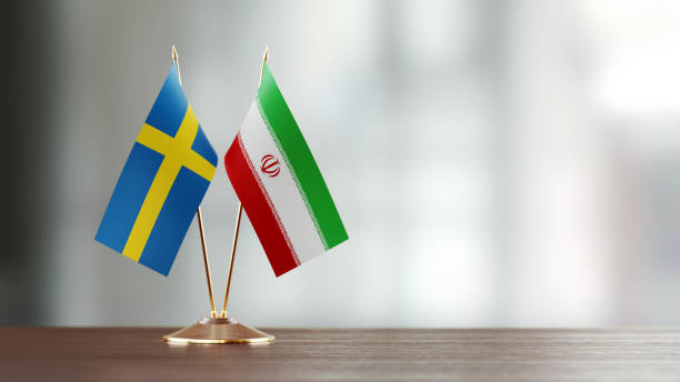 istock Swedish And Iranian Flag Pair On A Desk Over Defocused Background 932357354