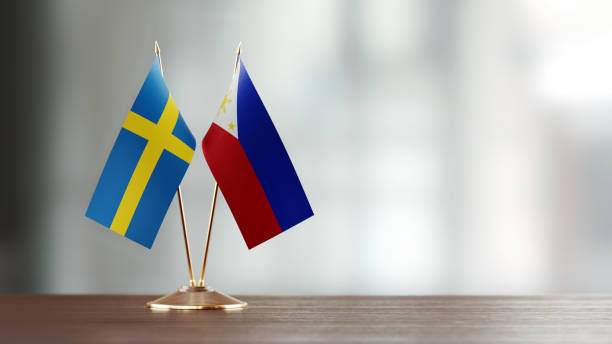 istock Swedish And Philippines Flag Pair On A Desk Over Defocused Background 932357972