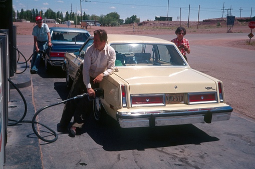 Arizona, 1981. Travelers with cars stop at a gas station and refuel their vehicles.