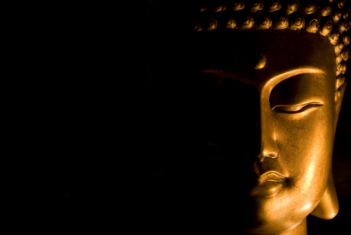 Picture of Buddha's Face lit from the side. The picture is isolated from the background and shows serenity and meditation.