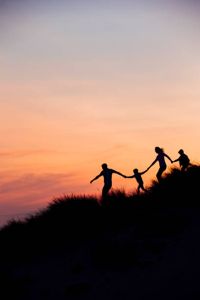 모래 언덕을 통해 실행 하는 가족의 실루엣 - family fun running couple 뉴스 사진 이미지