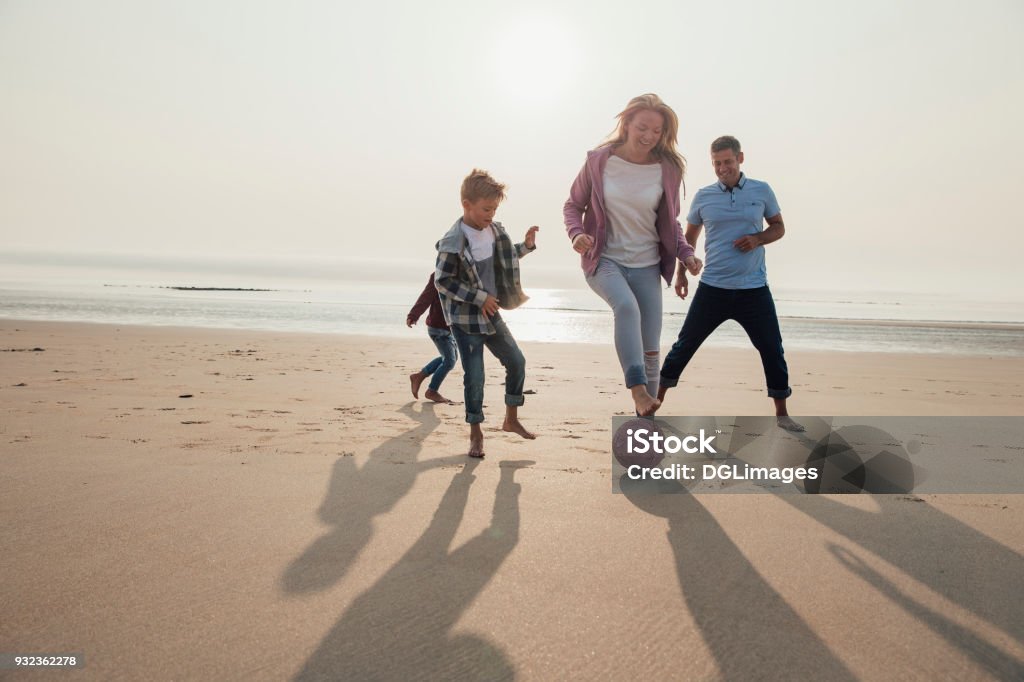 Mother Showing Football Tricks Mother showing off her football tricks while playing football at the beach with her family. Family Stock Photo