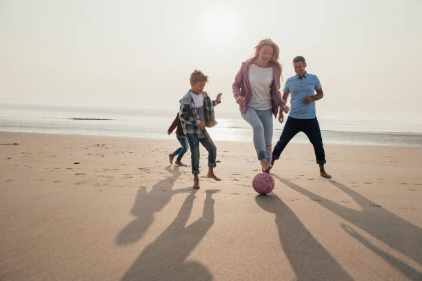 mother showing football tricks - beach two parent family couple family imagens e fotografias de stock