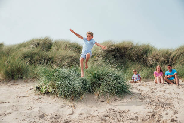 istock Little Boy Jumping Over a Sand Dune 932363198