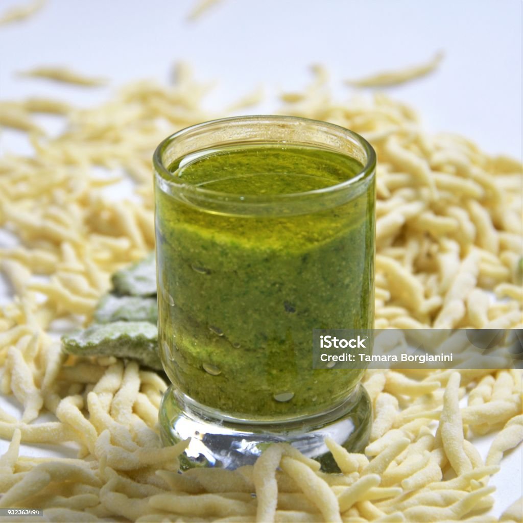 Fresh homemade pasta Italian trophy and agniolotti on a light background with traditional basilic souce pesto Fresh homemade uncooked pasta Italian trophy and green agnolotti and souce pesto on a light background with copyspace Appetizer Stock Photo