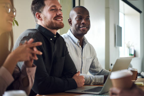 istock Diverse businesspeople smiling while sitting together in a boardroom 932364360