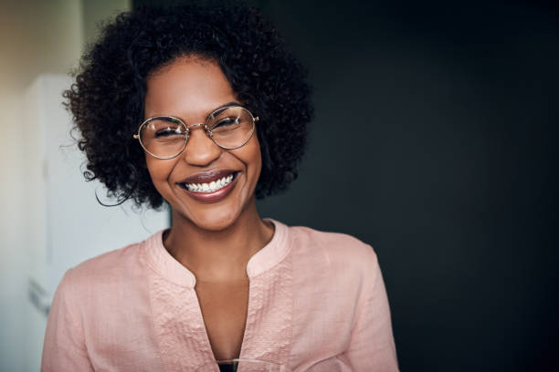 istock Laughing African businesswoman standing alone in a modern office 932367794