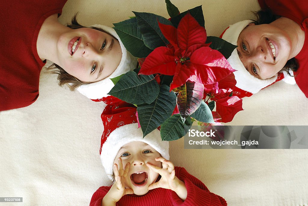 Familia espera en Euphorbia Pulcherrima para Navidad - Foto de stock de Adulto libre de derechos