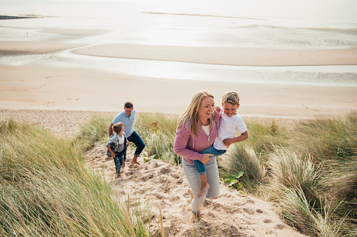 HIgh angle view of a family walking up the sand dune from the beach.