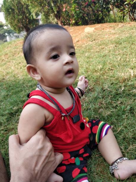 istock Cute little baby sitting on grass 932376158
