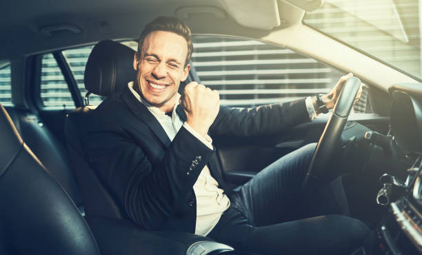 istock Ecstatic businessman fist pumping while driving in the city 932376790