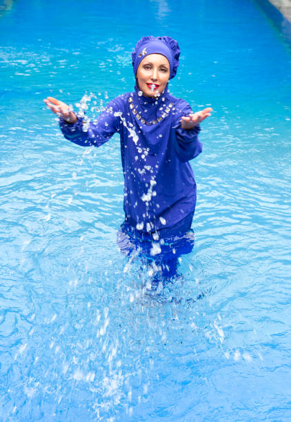 有吸引力的婦女在穆斯林泳裝 burkini 濺水在水池裡 - 回教泳裝 圖片 個照片及圖片檔
