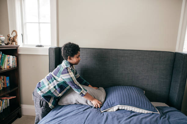 Boy making his bed stock photo