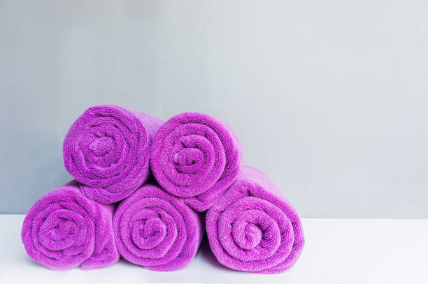istock Rolled up spa towels, Beach bath towel rolls purple fabric texture cloth background used for swimming pool 932389306