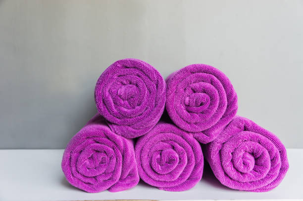 istock Rolled up spa towels, Beach bath towel rolls purple fabric texture cloth background used for swimming pool 932389330