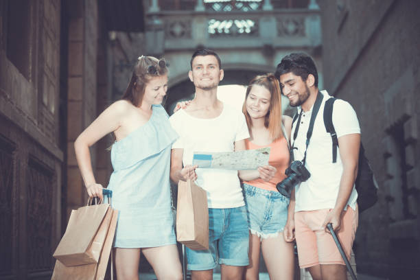 istock Group of young traveling people using paper map in city 932389508