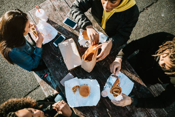gruppe junger erwachsener essen fast food - freunde imbiss großstadt stock-fotos und bilder