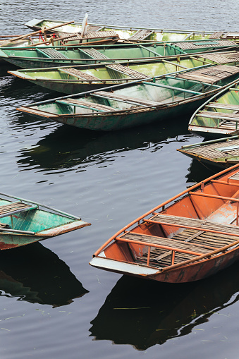 Red and green empty rowing boats stop over the river at Trang An Grottoes in Ninh Binh, Vietnam.