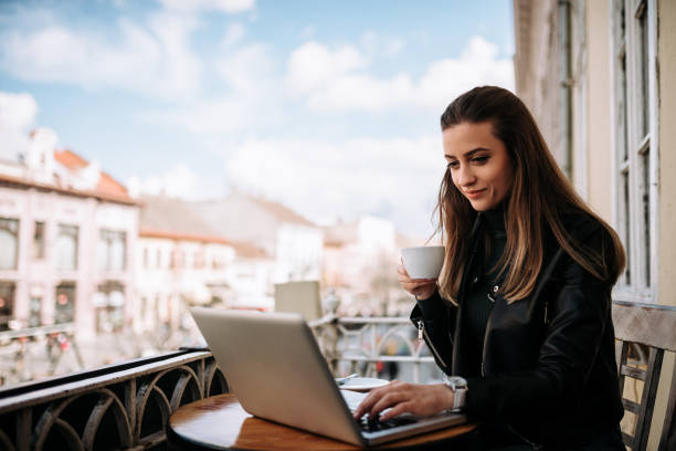 istock Freelance work concept. Woman working on a laptop and drinking coffee on the balcony. 932409060