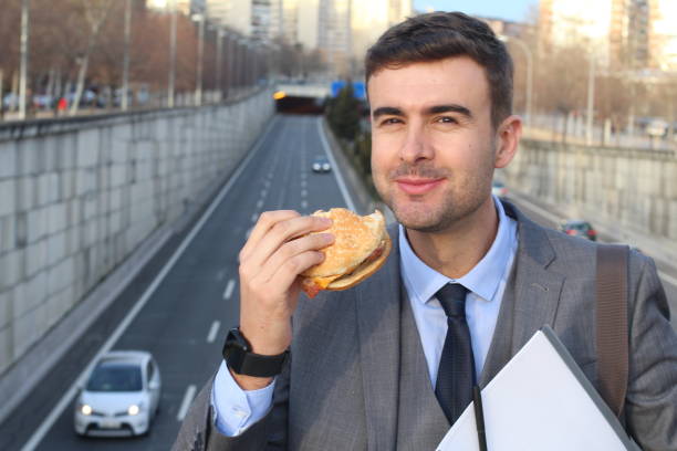 geschäftsmann mit fast-food in der stadt - eating sandwich emotional stress food stock-fotos und bilder