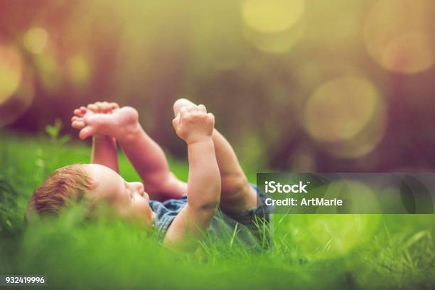 Cute Baby Playing With His Legs On The Grass Stock Photo - Download Image Now - Baby - Human Age, Child, Nature