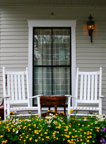 A porch with two chairs and a flower bed