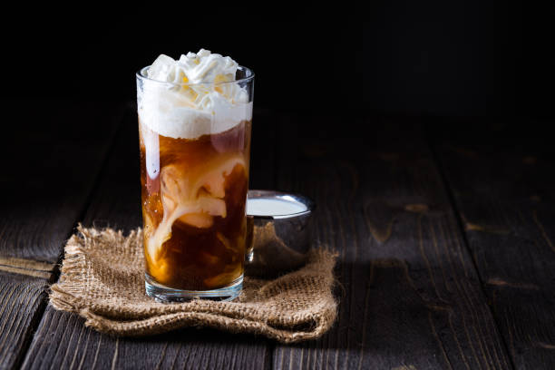 istock Iced coffee in a tall glass with cream poured over. 932429282