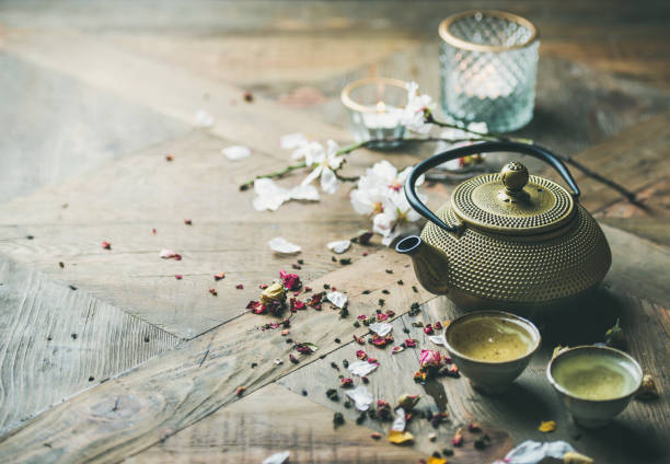 istock Iron teapot, cups, dried rose buds and candles, copy space 932436666