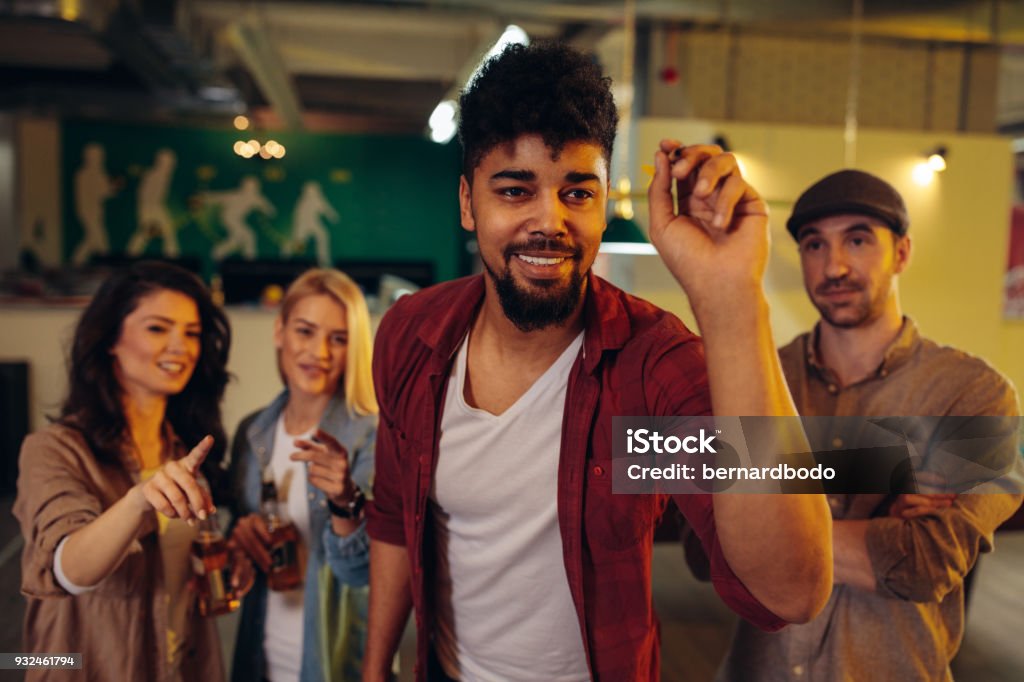 A flawless aim Group of friends playing darts Darts Stock Photo