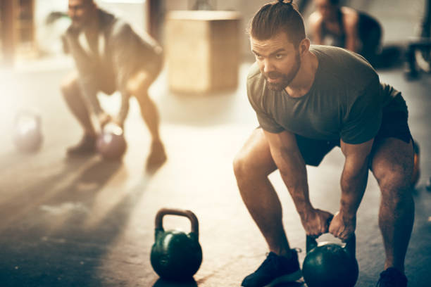 istock Man lifting dumbbells during a workout class at the gym 932463696