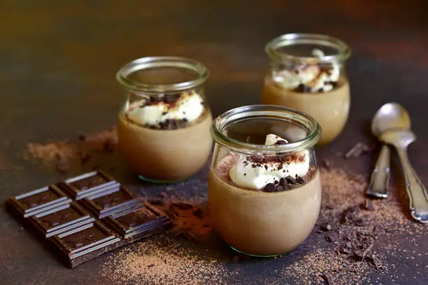 Chocolate coffee panna cotta in a vintage glass jar on a dark slate background.