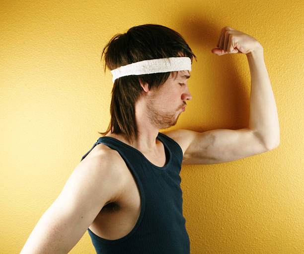 Man posing in retro workout clothes flexing muscle stock photo