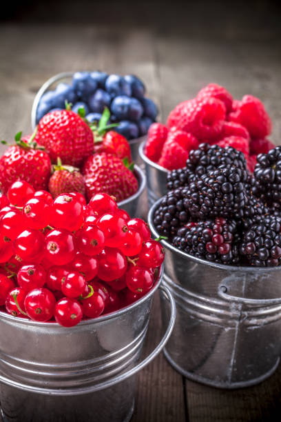 istock Berries close up assortment in tin cans on rustic wooden table 932478558