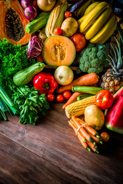istock Assorted organic tropical fruits and vegetables in a rustic kitchen background. Natural lighting 932495098