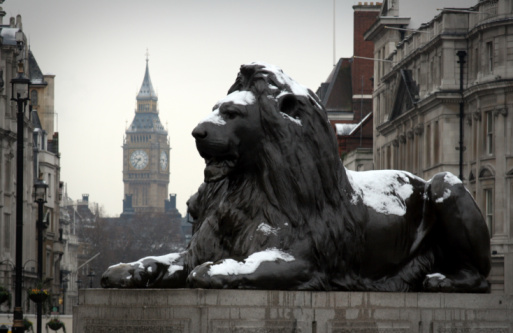 Trafalgar Square lions covered in snow with Big Ben in the background