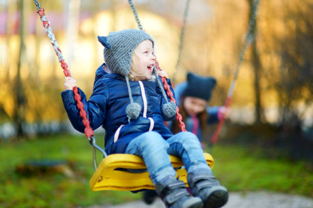 niña linda que se divierten en un columpio - child swing swinging spring fotografías e imágenes de stock